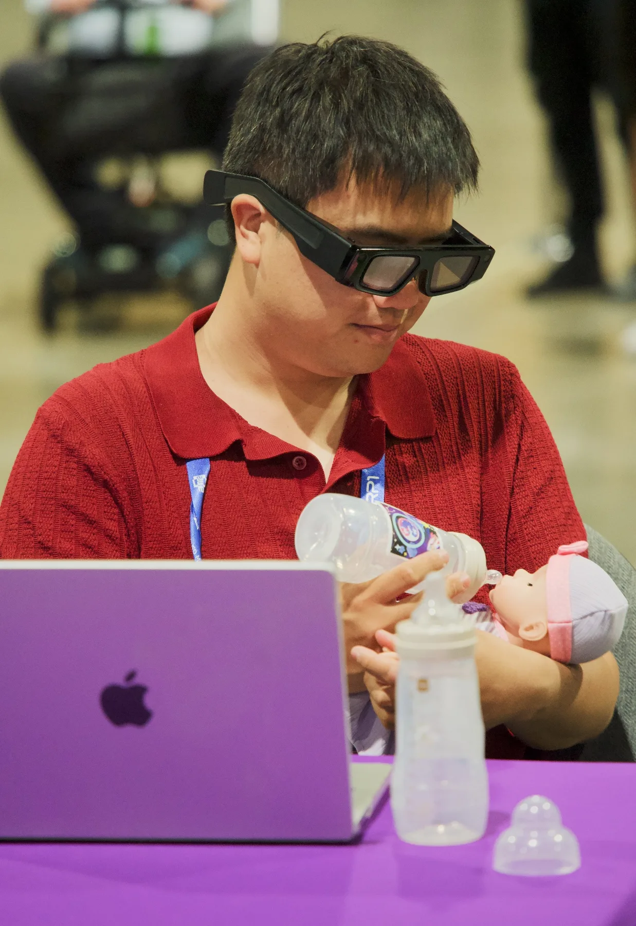 A participant wearing Snap Spectacles bottle-feeds a baby doll while testing the CareNest AR experience